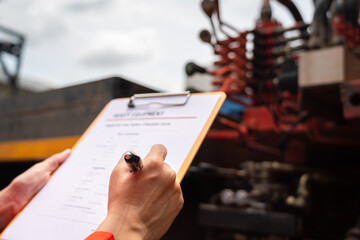 A mechanical engineer is inspecting the condition of truck crane vehicle (as blurred background)...