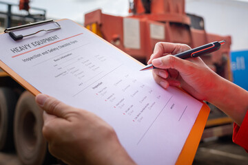 A mechanical engineer is inspecting the condition of truck crane vehicle (as blurred background)...