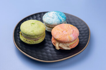 Delicious macarons in a plate on a blue background