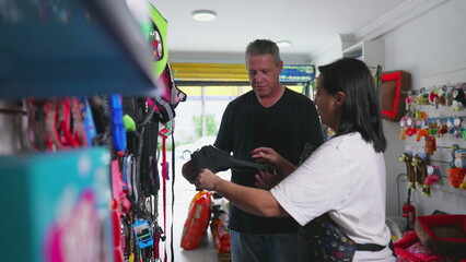 Customer Shopping at Pet Shop Business Owner Assisting Man in Dog Item Selection