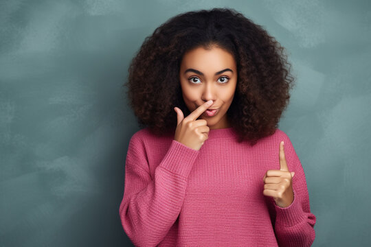 Hipster teen gen z black american girl showing shh sign finger gesture asking to keep secret, be hush silent or privacy silence on urban wall background. Teenage problem secrecy concept.
