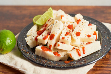Mexican Traditional snack, jicama or yam bean, with chili, chamoy, sauce and lime