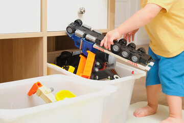 Putting toys back in the box is an important lesson in responsibility for a child. Kid toddler boy...