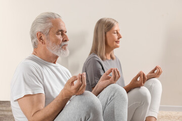 Senior couple practicing yoga at home, selective focus