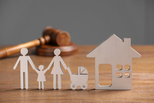 Family law. Figure of parents with children, house model and gavel on wooden table