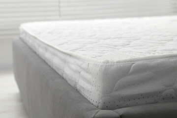 Fototapeta na wymiar New light green mattress on gray bed indoors, closeup. Space for text