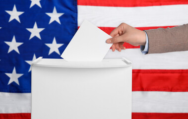 Woman putting her vote into ballot box against national flag of United States, closeup