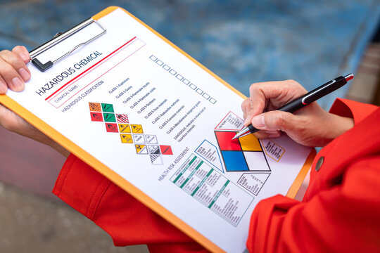 A safety engineer is using pen to rating the health risk assessment level of chemical hazardous material in the paperwork form. Industrial safety working scene, close-up and selecitve focus.