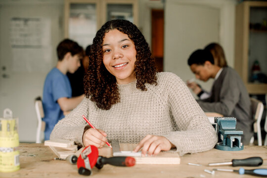 Portrait of smiling female teenage student during carpentry class at high school