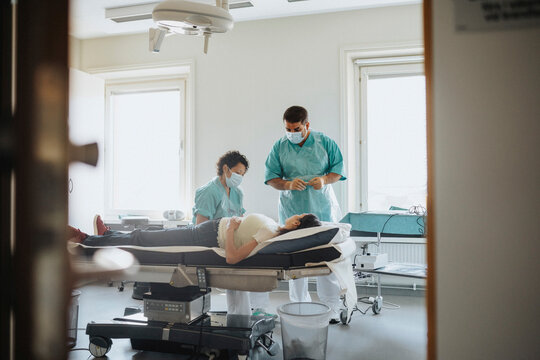 Male and female surgeons examining patient on bed in hospital
