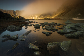 Lake in the mounstains with peaks in background luminated by sunrise