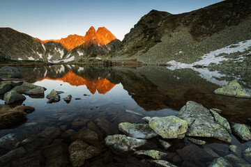 Lake in the mounstains with peaks in background luminated by sunrise