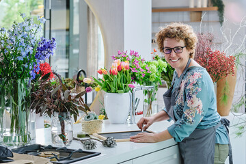 Positive mature woman working in floral shop