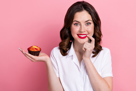 Photo of cute tricky woman dressed white shirt finger lips mouth holding hand arm small cupcake isolated pink color background