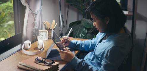 Asian children using digital tablet with stylus pen write and do homework at home. Stress Thai...