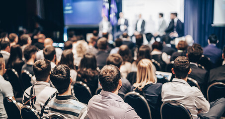 Speaker giving a talk in conference hall at business event. Rear view of unrecognizable people in audience at the conference hall. Business and entrepreneurship concept