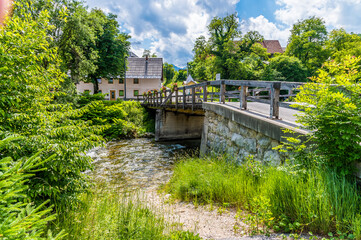 Fototapeta premium A view across a bridge over the Mostnica river in the alpine village of Stara Fuzina above lake Bohinj in Slovenia in summertime