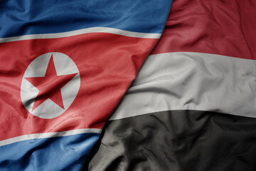 big waving realistic national colorful flag of north korea and national flag of yemen .