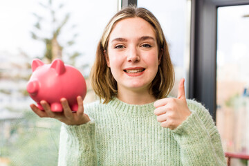 pretty young woman with a piggy bank. savings concept. house interior design