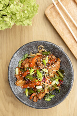 A bowl of udon noodles, veal and fried vegetables top view on wooden table