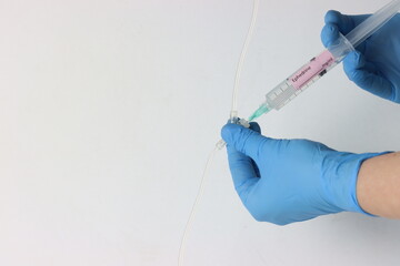Professional wearing gloves injecting ephedrine into a intravenous set.