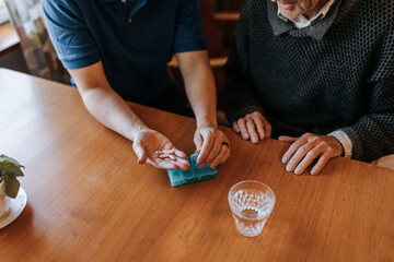 High angle view of female caregiver helping senior man while having medicines at home