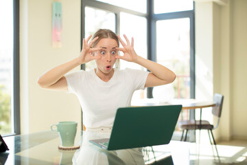 caucasian pretty woman with a laptop keeping an eye on you, not trusting, watching and staying...