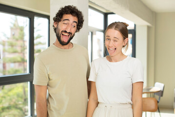 young adult couple with cheerful, carefree, rebellious attitude, joking and sticking tongue out, having fun