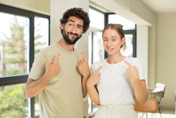 Fototapeta premium young adult couple with a bad attitude looking proud and aggressive, pointing upwards or making fun sign with hands