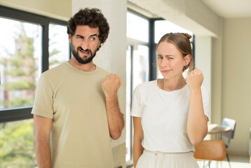 Obraz premium young adult couple looking confident, angry, strong and aggressive, with fists ready to fight in boxing position