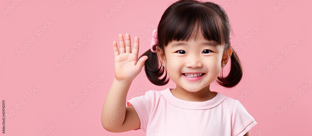 Poster joyful asian girl displaying open palm with copy space on a pink background