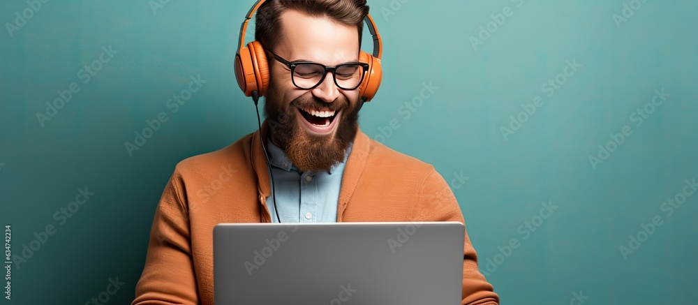 Poster A happy bearded young man with laptop smiling and pointing to the side and upwards displaying an object in empty area