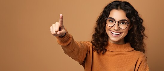 Smiling young woman happily points upwards to show an object - obrazy, fototapety, plakaty