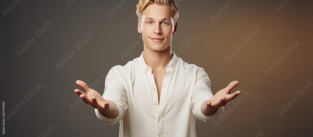 Poster Young adult man with blond hair holding an object and presenting it on a blank background