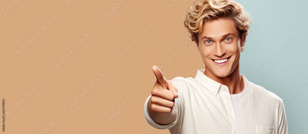 Poster happy and satisfied young man casually pointing to empty space with a cheerful smile