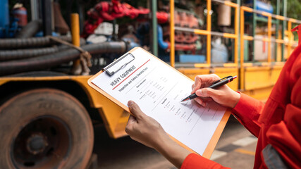 A mechanical engineer is checking on heavy machine and equipment inspection checklist form with the...