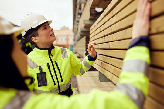 Female workers examining planks stacked at industry