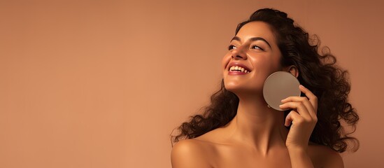 Plus size Latin woman enjoying new organic skincare routine looking at mirror in brown studio Self care concept