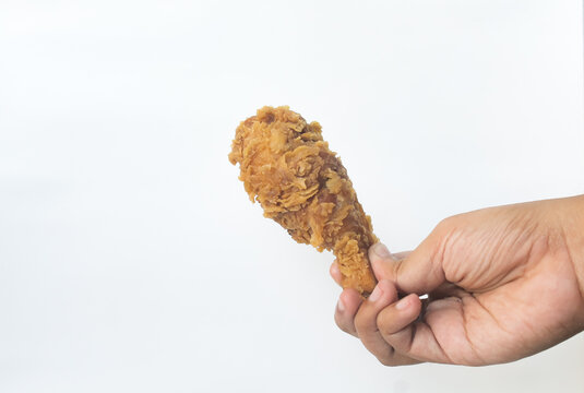 Hand hold fried chicken leg isolated in white.
