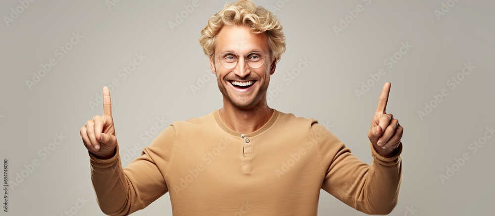 Fototapete blond man joyfully pointing with both hands towards an object