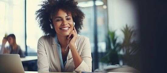 African American businesswoman smiles while working speaking on the phone and making notes in her office