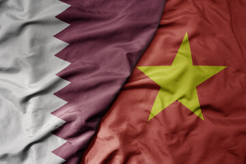 big waving realistic national colorful flag of qatar and national flag of vietnam .
