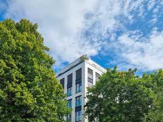 Facade of a modern building behind green trees
