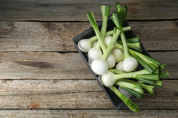 Black crate with green spring onions on wooden table, top view. Space for text - obrazy, fototapety, plakaty