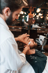 Sitting on the chair. Man is visiting modern barber shop. Modern style