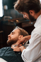 Getting shaved. Man is visiting modern barber shop. Modern style