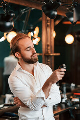 Hair clipper is in hand. Handsome barber is in the salon