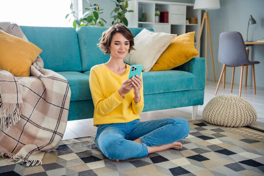 Photo of lovely pretty peaceful positive gorl use phone communicate friend sitting carpet loft interior flat indoor