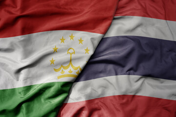 big waving realistic national colorful flag of tajikistan and national flag of thailand .