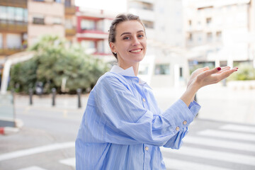 Fototapeta premium pretty woman feeling happy and cheerful, smiling and welcoming you, inviting you in with a friendly gesture
